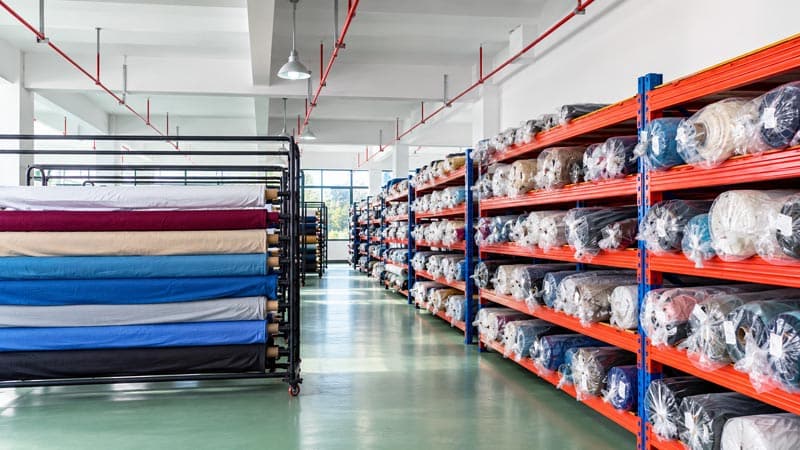 Novo espaço, novo visual! A BEGOODTEX tem uma nova casa! 5 Rolos de tecido begoodtex dispostos em suportes móveis na zona de armazenamento de tecidos